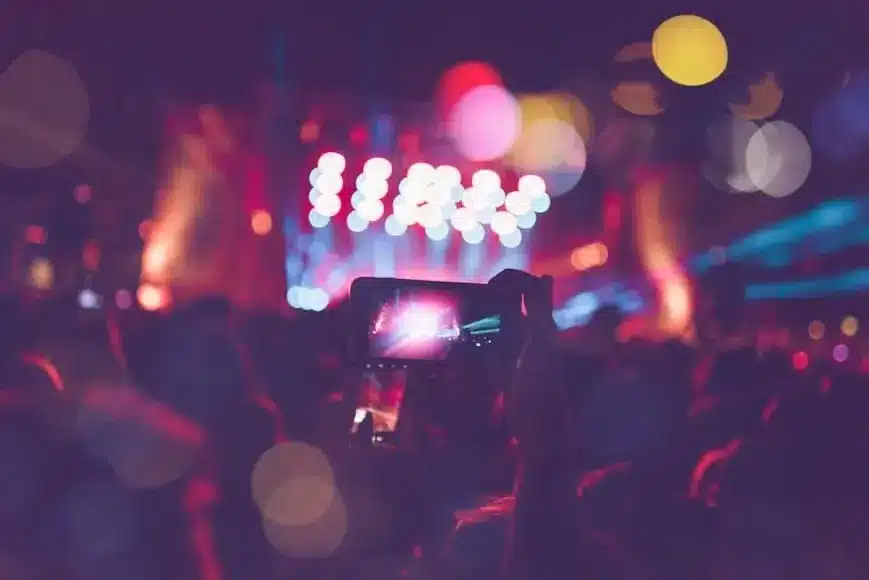 Silhouettes of festival concert crowd in front of bright stage lights Unrecognizable people and colorful effects.